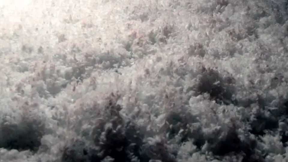 Lana mineral blanca insuflada rellenando una cámara bajo cubierta